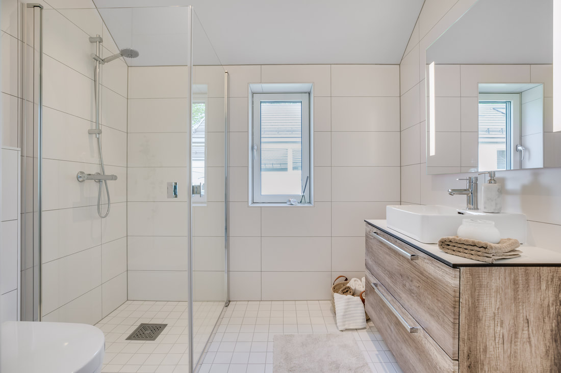 Moderne bad med dusj med store hvite fliser i Bringebærhagen
