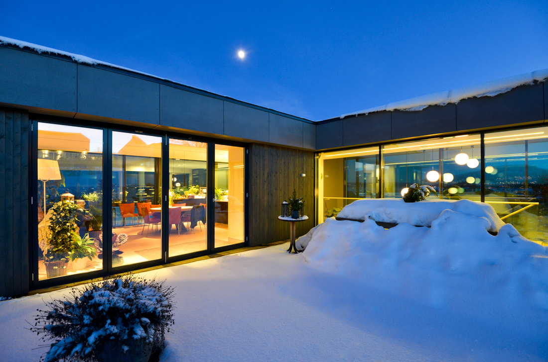 Snøfyllt uteplass med varmt lys og gjennomsyn inne på Trosvikodden 10